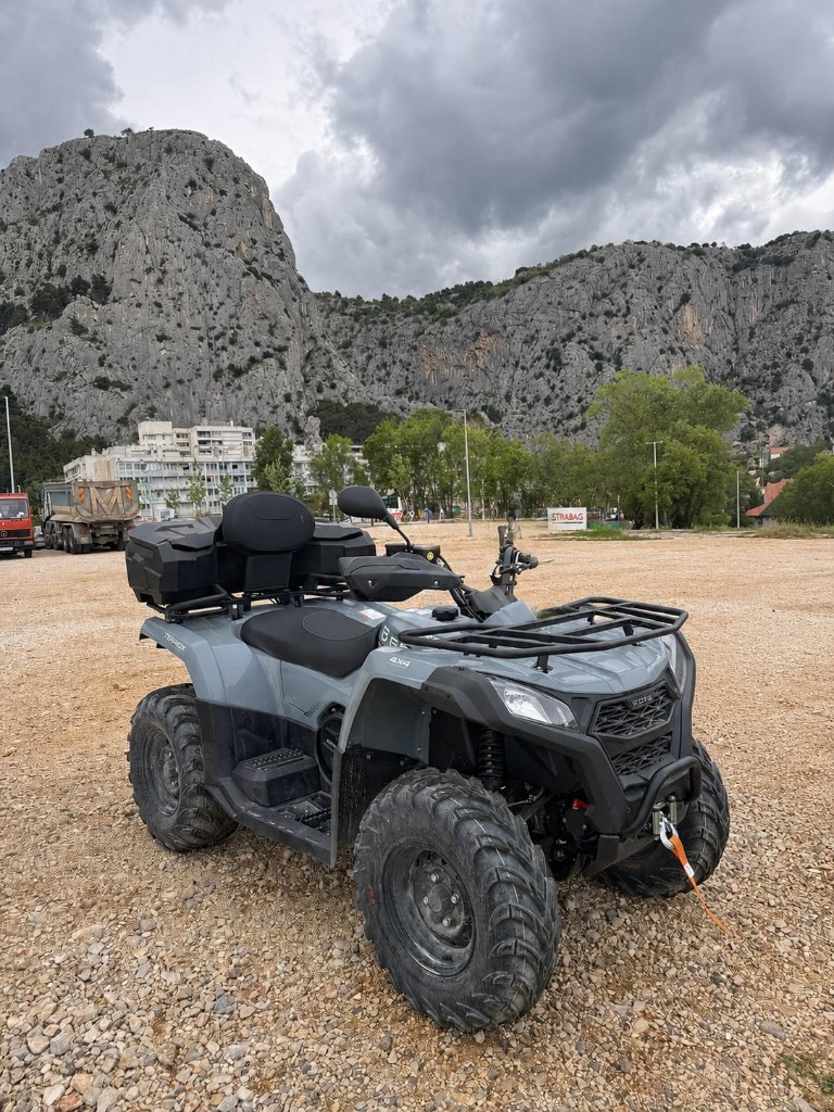 Grey quad bike on gravel with limestone cliffs near Omiš, Croatia